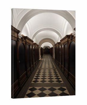 Arched corridor in a historic Viennese building featuring carved wooden shelves, black-and-white diamond tile floor, and ornate white arched ceiling in a grand interior.