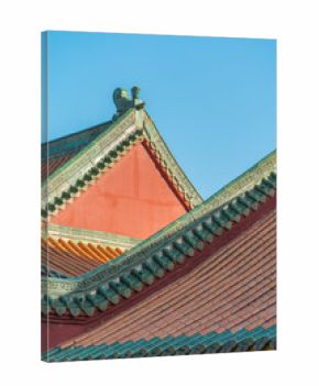 Red building roofs with green decorative trim under a clear blue sky.Traditional Chinese wooden-structure architecture