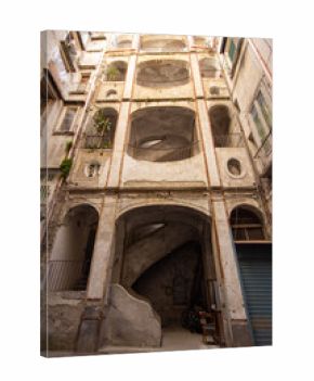 A dramatic, low-angle view of a crumbling Neapolitan courtyard reveals layered arches, balconies, and a worn spiral staircase. Perfect for cultural travel blogs, historical architecture presentations,