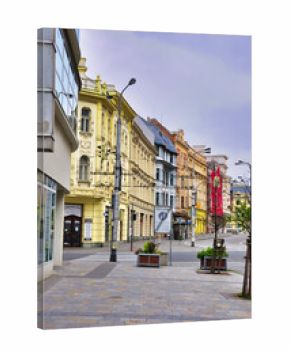 Osrtava - Tętniąca życiem ulica z pastelowymi fasadami, dekoracyjną architekturą i strefą dla pieszych wzdłuż brukowanego chodnika.