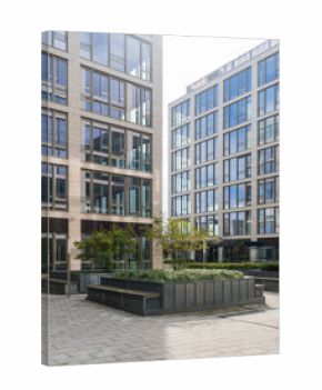 Modern office buildings with glass facades surrounding a courtyard with greenery and seating areas