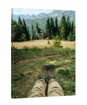 Trekking boots lying on grass with mountain view, retro tone