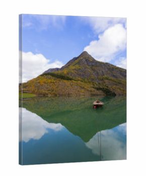 Autumn landscape in Skjolden, South Norway, with a calm lake reflecting the mountains and colorful foliage.