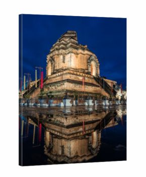 Majestic Wat Chedi Luang in Chiang Mai, Thailand, illuminated at dusk. The ancient Buddhist temple's intricate architecture is perfectly mirrored in the tranquil water, highlighting its spiritual and