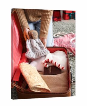 Woman packing warm clothes, passport and Christmas decor into suitcase at home, closeup