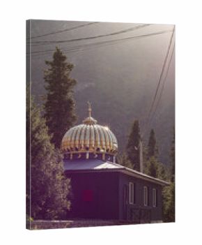 mosque with golden dome surrounded by mountains and trees shining in the sunlight