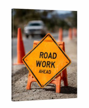 Road work sign with cones on a highway, cautioning drivers.