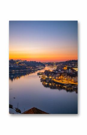 Sunset over Porto, Portugal, with sky colors and city lights reflecting on the Douro River and traditional architecture along the waterfront