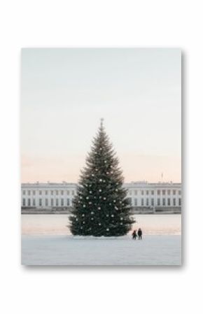 A tall, decorated Christmas tree stands in the snow, with two figures walking in the distance.