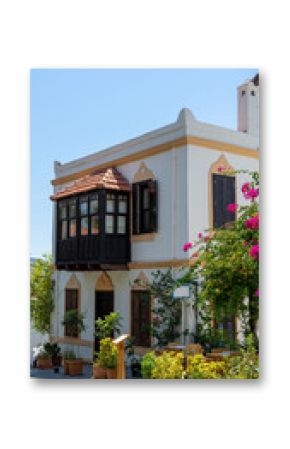 Mediterranean style house with wooden balcony surrounded by green plants and bougainvillea in Kas, Turkey. Walking around city. Vertical image