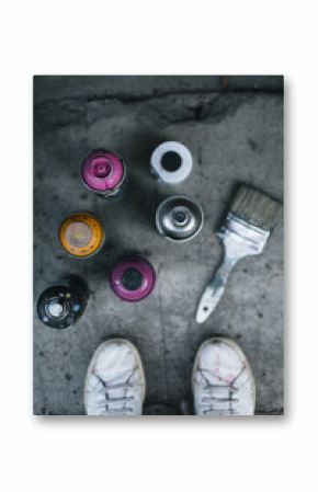 Spray paint cans and brush on sidewalk  