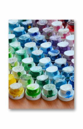 A pattern from a many nozzles from a paint sprayer for drawing graffiti, smeared into different colors. The plastic caps are arranged in many rows forming the color of the rainbow