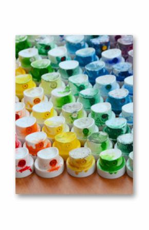 A pattern from a many nozzles from a paint sprayer for drawing graffiti, smeared into different colors. The plastic caps are arranged in many rows forming the color of the rainbow