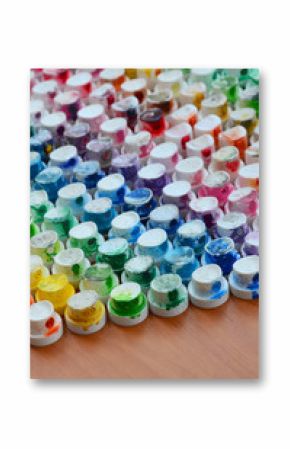 A pattern from a many nozzles from a paint sprayer for drawing graffiti, smeared into different colors. The plastic caps are arranged in many rows forming the color of the rainbow