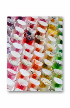 A pattern from a many nozzles from a paint sprayer for drawing graffiti, smeared into different colors. The plastic caps are arranged in many rows forming the color of the rainbow