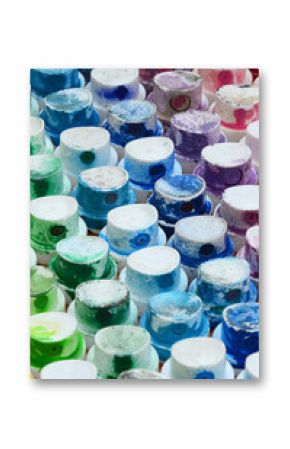 A pattern from a many nozzles from a paint sprayer for drawing graffiti, smeared into different colors. The plastic caps are arranged in many rows forming the color of the rainbow
