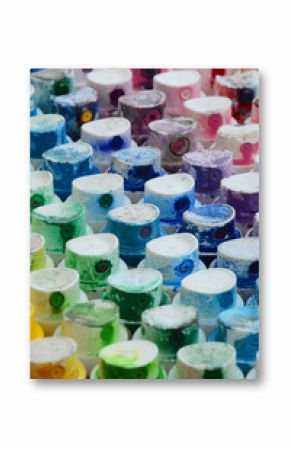 A pattern from a many nozzles from a paint sprayer for drawing graffiti, smeared into different colors. The plastic caps are arranged in many rows forming the color of the rainbow