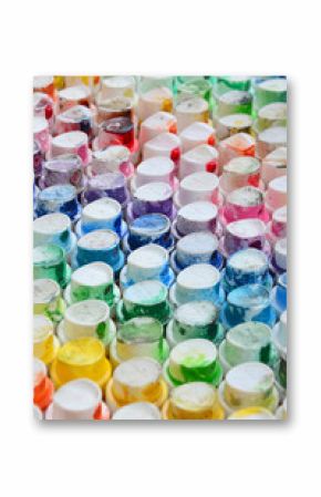 A pattern from a many nozzles from a paint sprayer for drawing graffiti, smeared into different colors. The plastic caps are arranged in many rows forming the color of the rainbow