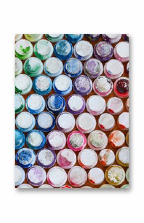 A pattern from a many nozzles from a paint sprayer for drawing graffiti, smeared into different colors. The plastic caps are arranged in many rows forming the color of the rainbow