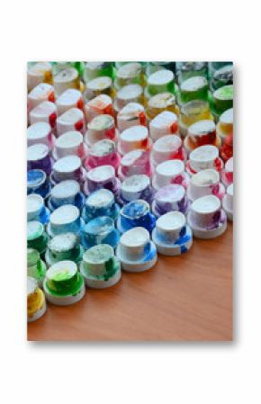 A pattern from a many nozzles from a paint sprayer for drawing graffiti, smeared into different colors. The plastic caps are arranged in many rows forming the color of the rainbow