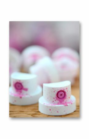 The soiled pink nozzles from the paint sprayer lies on a wooden plank on a background of a many dirty spray cans