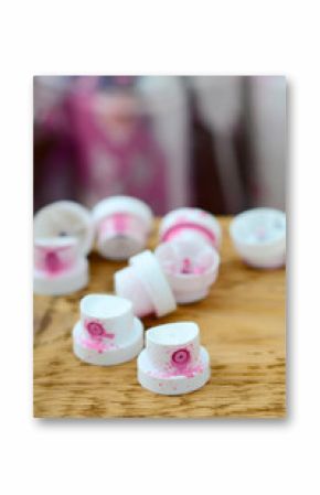 The soiled pink nozzles from the paint sprayer lies on a wooden plank on a background of a many dirty spray cans