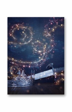 low key image of beautiful queen or king crown next to sword. fantasy medieval period. Selective focus
