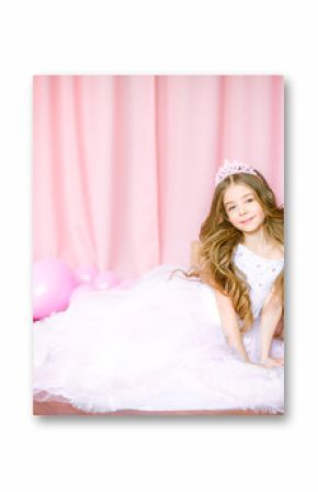 Girl with blond long hair in light-pink dress of a princess and tiara with balloons around