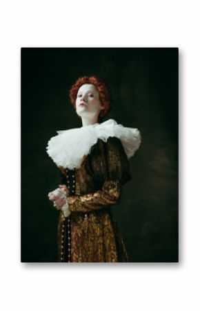 I make decisions. Medieval redhead young woman in golden vintage clothing as a duchess standing crossing hands on dark green background. Concept of comparison of eras, modernity and renaissance.