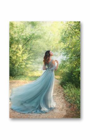 fairy tale princess in light summer blue, turquoise dress standing in park. Happy Woman walks towards wind, graceful dancing girl goddess in image of flower. flying long hem of dress. nymph of forest