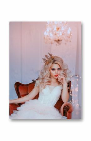 Angry young beautiful girl princess misses sadness loneliness. Queen woman blonde woman long curls hair. Hairstyle with vintage royal crown. Backdrop white room, candelabra romantic lit bright sparks