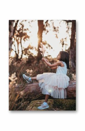 Little girl sitting on a tree trunk in golden hour