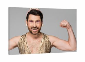 bearded man with toy crown on head and princess dress costume showing muscles isolated on grey, banner.