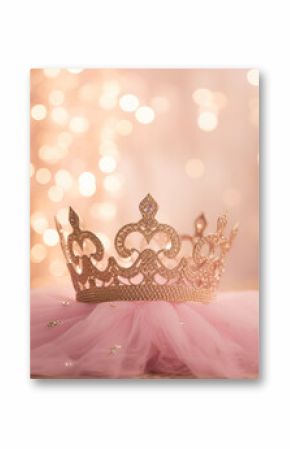 Princess birthday party: golden bedazzled princess crown on a pink tulle fabric with golden bokeh background