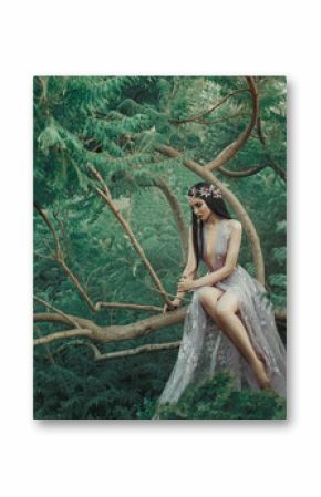 Fantasy girl in a fairy garden. A young princess in a purple dress sits on a green tree branch. Creative colors artistic processing. Fantasy woman image elf queen, forest nymph. Sexy gown costume