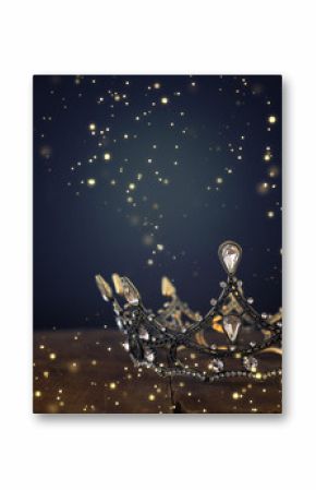 low key image of beautiful queen/king crown over wooden table. vintage filtered. fantasy medieval period. Glitter sparkle lights