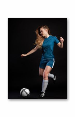 young woman football player kicking ball isolated on black background