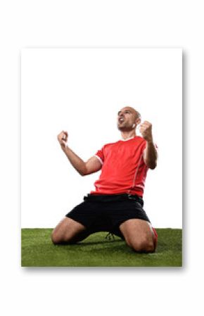 happy and excited football player in red jersey celebrating scoring goal kneeling on grass pitch