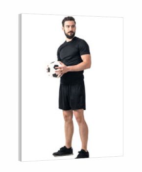 Strong confident soccer player holding ball with both hands looking away. Full body length portrait isolated over white background.