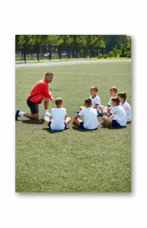 Portrait of boys sitting in front of coach on football field listening to pre game lecture