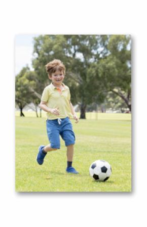 little kid 7 or 8 years old enjoying happy playing football soccer at grass city park field running and kicking the ball excited in childhood sport passion