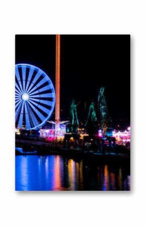 Colorful Szczecin by the river Oder at night. City at night and neon lights, ferris wheel and bridge. Poland, summer 2022 