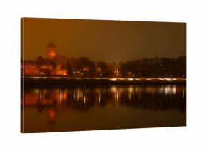 Toruń nocą, stare miasto nad rzeką Wisłą, światła odbijające się w wodzie. 