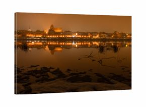 Toruń nocą, stare miasto nad rzeką Wisłą, światła odbijające się w wodzie. 