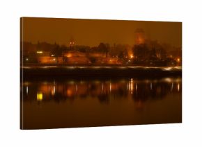 Toruń nocą, stare miasto nad rzeką Wisłą, światła odbijające się w wodzie. 