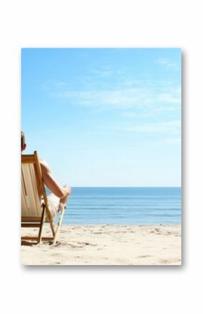Man relaxing on beach chair looking at the ocean on a sunny day. Serene and peaceful scene