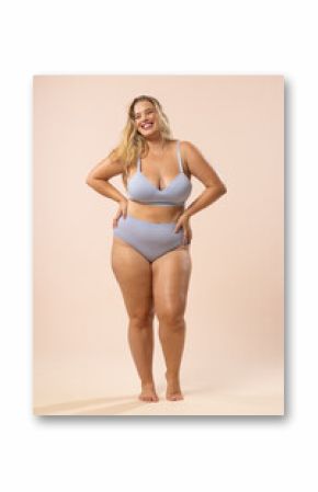 Caucasian plus-size child model in light blue underwear on beige background, copy space