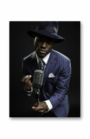 Black man with blue striped suit and blue hat singing.