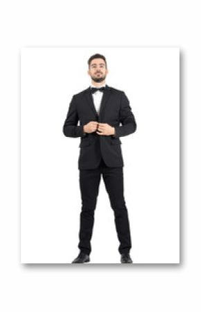 Young bearded wealthy man buttoning tuxedo with bow tie. Full body length portrait isolated over white studio background.