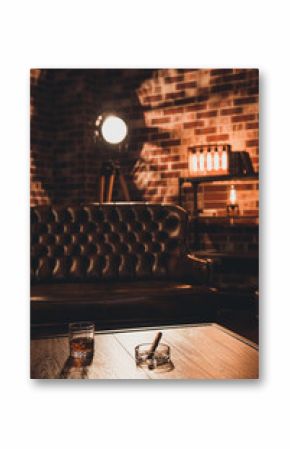 Loft interior. Leather couch with glass of whiskey and cigar on